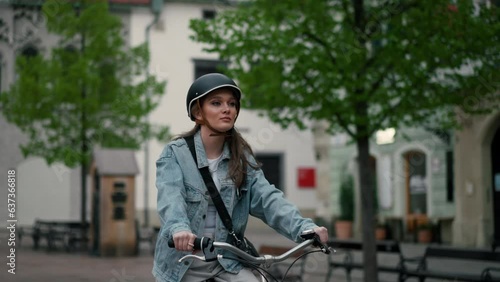 Serious girl in helmet riding bicycle on urban street of Europe photo