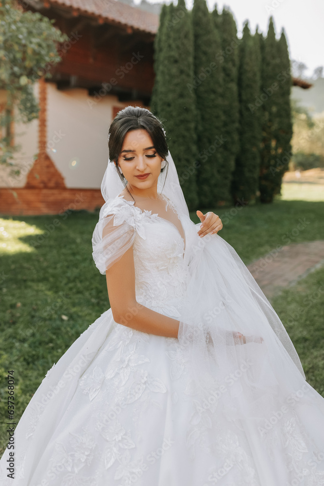 Beautiful bride in a fashionable wedding dress on a natural background in the park. A stunning young bride is incredibly happy. Happy girl on her wedding day