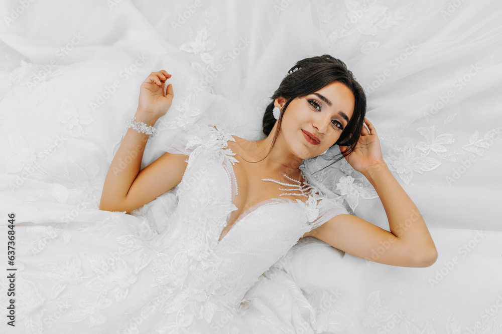 young beautiful bride in a wedding dress lying down, fashion. The photo is taken from above. Near the wedding dress. A dreamy bride is enjoying her wedding young beautiful bride in a wedding dress lying down, fashion. The photo is taken from above. Near the wedding dress. A dreamy bride is enjoying her wedding