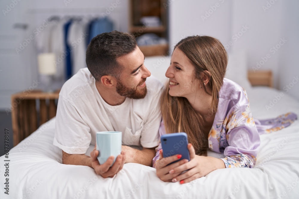 Man and woman couple drinking coffee using smartphone at bedroom Man and woman couple drinking coffee using smartphone at bedroom
