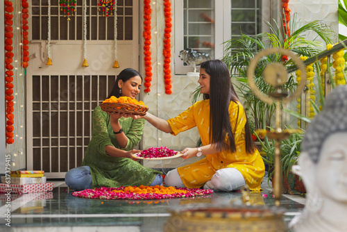 Two sister  making a rangoli of flower at home on the occasion of Diwali photo