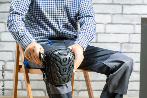 Builder wearing knee protection pads. Concept of safety protective equipment at construction site. Safety at work.