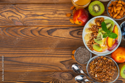 Bowl of granola with yogurt and fresh berries on a texture table. Yogurt berries, acai bowl, spirulina bowl. Healthy food, balanced breakfast. Strawberries, blueberries, kiwi, peach, almonds and chia.