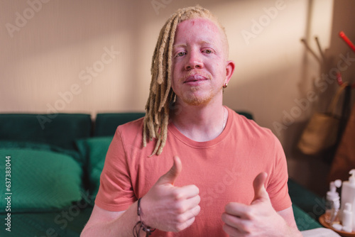 Homem albino sentado na cama dando sinal de positivo. photo