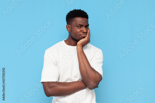 Fotografi displeased young guy african american in a white t-shirt is sad and bored on blu