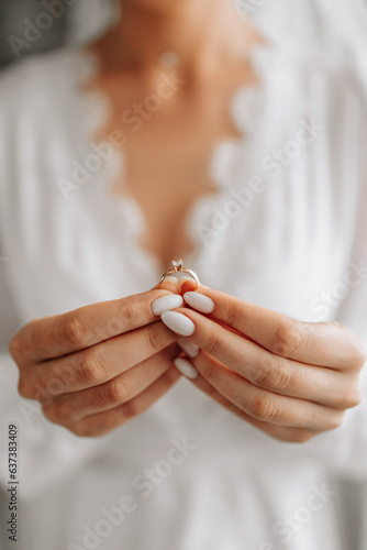 The bride is holding a gold ring in her hands, close-up. Morning of the bride. Wedding day. Open shoulders. Sexy girl