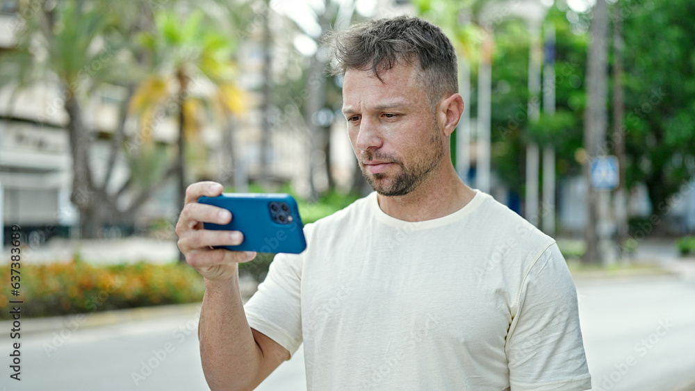 Fototapeta premium Young man using smartphone with serious expression at park