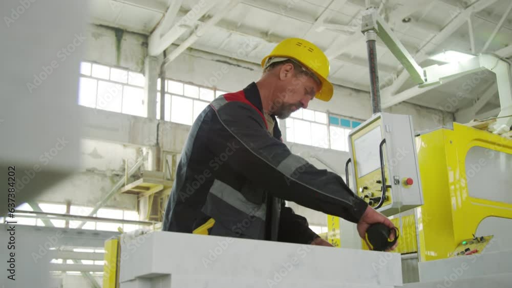 Low angle shot of mature male worker in hardhat and uniform measuring marble slab with tape during workday at stone factory Low angle shot of mature male worker in hardhat and uniform measuring marble slab with tape during workday at stone factory