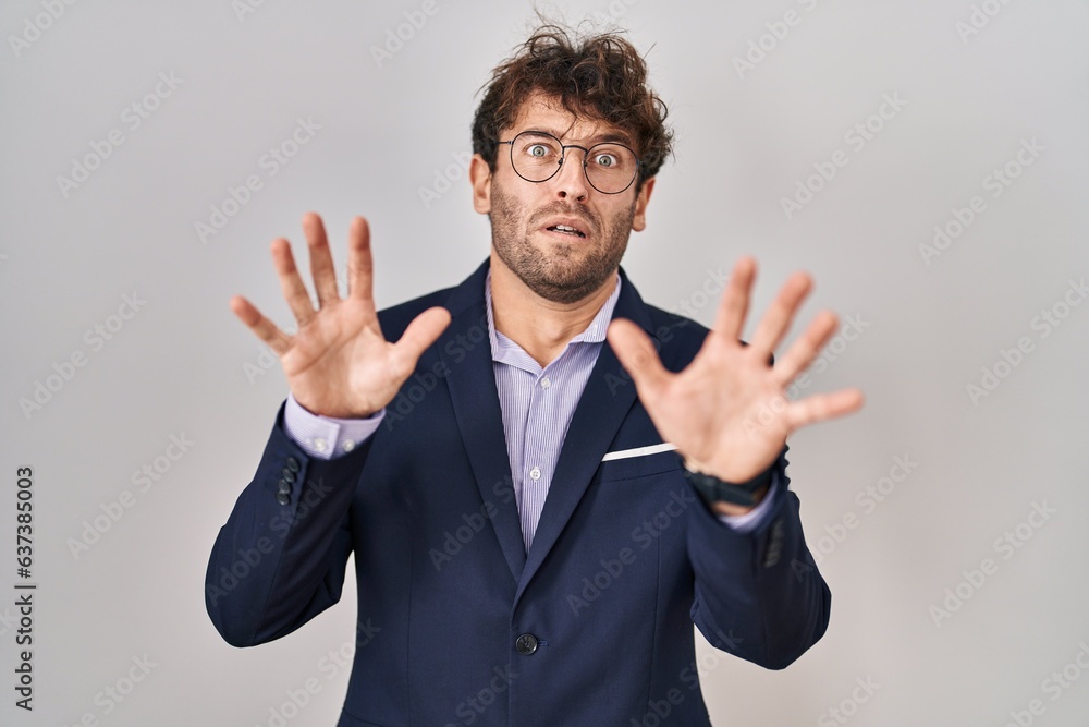 Hispanic business man wearing glasses afraid and terrified with fear expression stop gesture with hands, shouting in shock. panic concept. Hispanic business man wearing glasses afraid and terrified with fear expression stop gesture with hands, shouting in shock. panic concept.