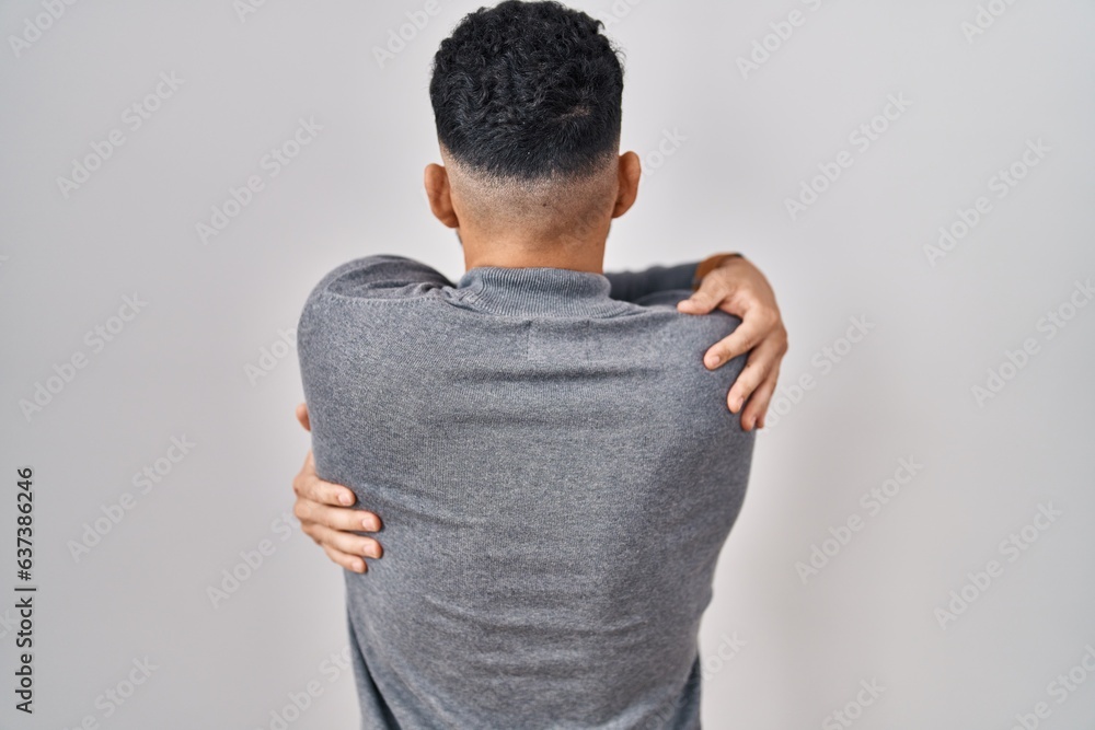 Hispanic man with beard standing over white background hugging oneself happy and positive from backwards. self love and self care Hispanic man with beard standing over white background hugging oneself happy and positive from backwards. self love and self care
