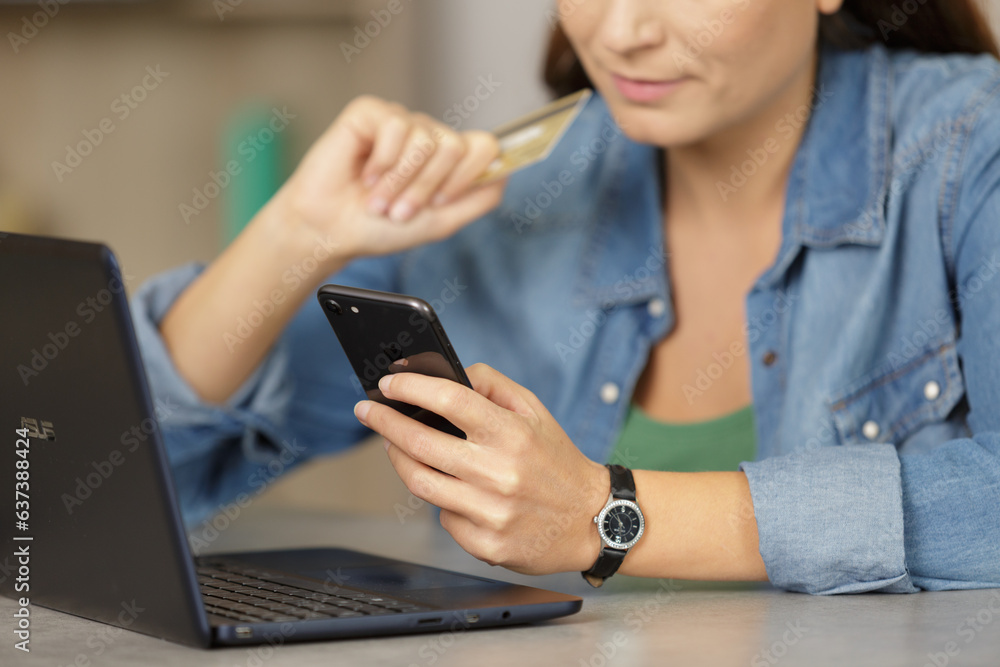 woman buying online payment on laptop reading credit card number woman buying online payment on laptop reading credit card number
