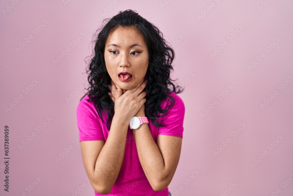 Young asian woman standing over pink background shouting suffocate because painful strangle. health problem. asphyxiate and suicide concept. Young asian woman standing over pink background shouting suffocate because painful strangle. health problem. asphyxiate and suicide concept.