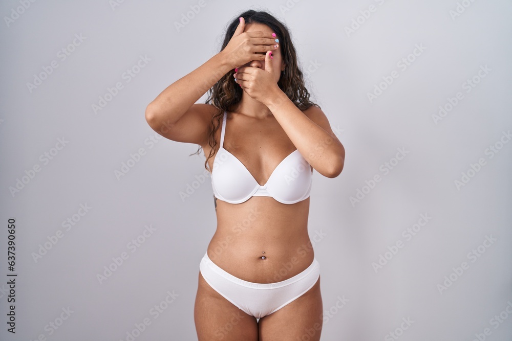 Φωτογραφία Young hispanic woman wearing white lingerie covering eyes and mouth with hands, surprised and shocked