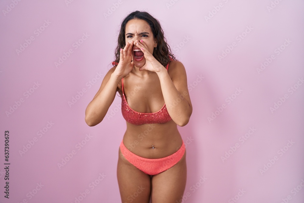 Young hispanic woman wearing lingerie over pink background shouting angry out loud with hands over mouth Young hispanic woman wearing lingerie over pink background shouting angry out loud with hands over mouth