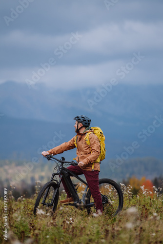 Active man on bike in the middle of autumn nature, admire mountains. Healthy lifestlye concept.