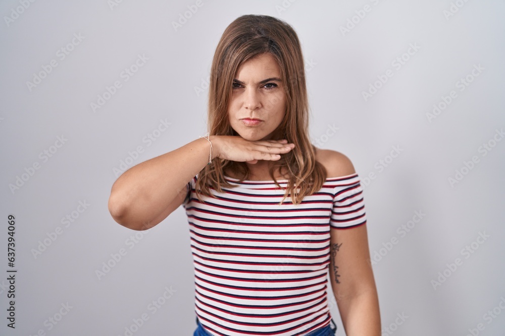 Young hispanic woman standing over isolated background cutting throat with hand as knife, threaten aggression with furious violence Young hispanic woman standing over isolated background cutting throat with hand as knife, threaten aggression with furious violence
