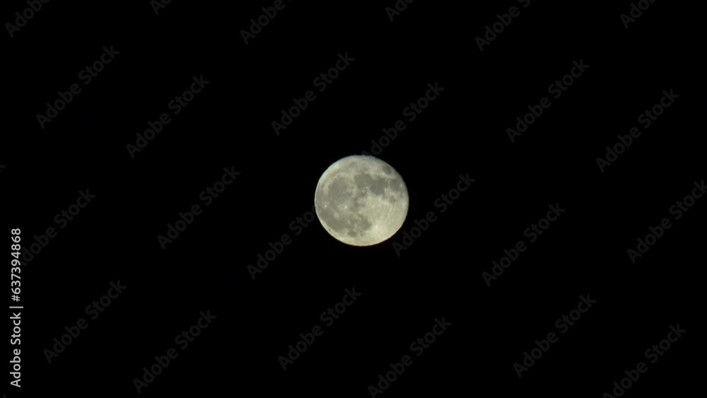 A telephoto shot of a full moon shining above, the moon is in the center of the frame. A telephoto shot of a full moon shining above, the moon is in the center of the frame.