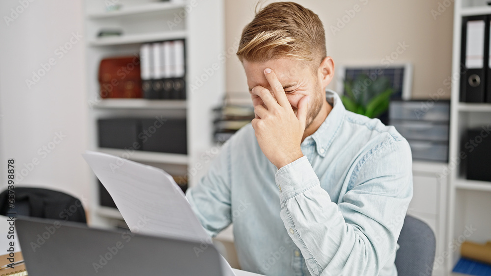 Young caucasian man business worker using laptop reading document stressed at office Young caucasian man business worker using laptop reading document stressed at office