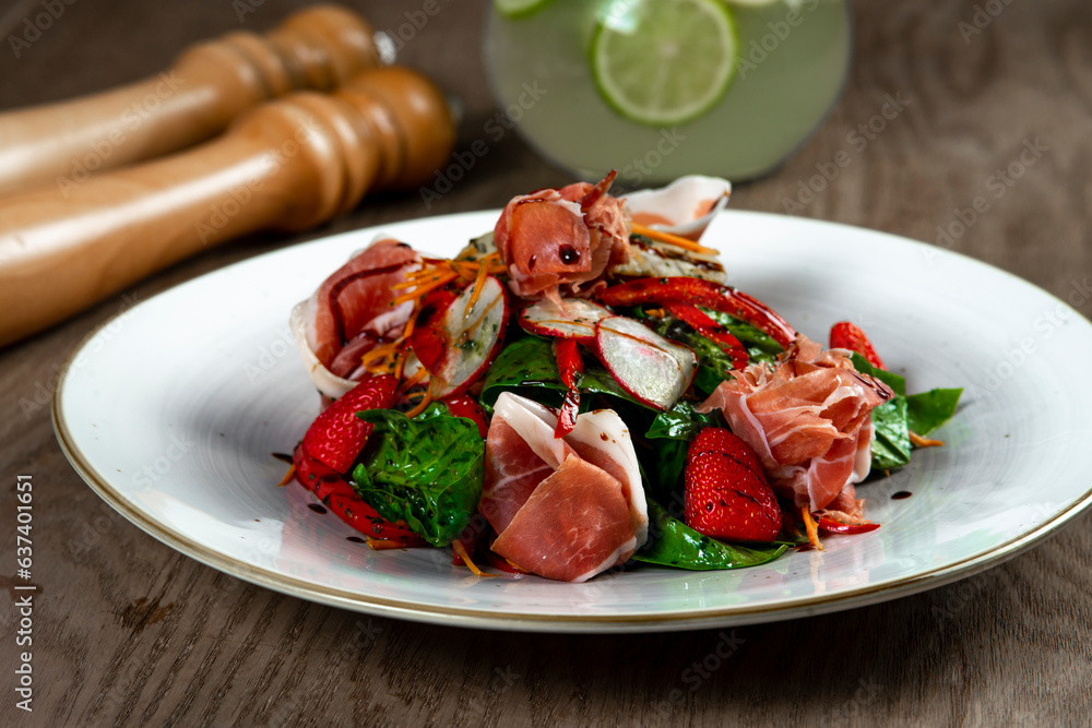 salad with ham, spinach and mozzarella on wooden table