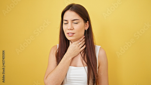 Young beautiful hispanic woman touching neck over isolated yellow background