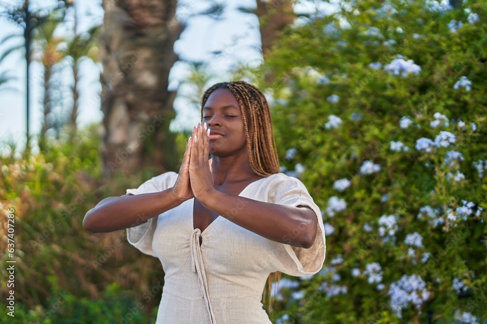 African american woman praying with closed eyes at park African american woman praying with closed eyes at park