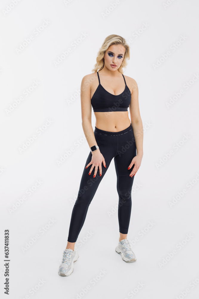 Sexy athletic woman in a black tracksuit on a white background. Athletic physique Sexy athletic woman in a black tracksuit on a white background. Athletic physique