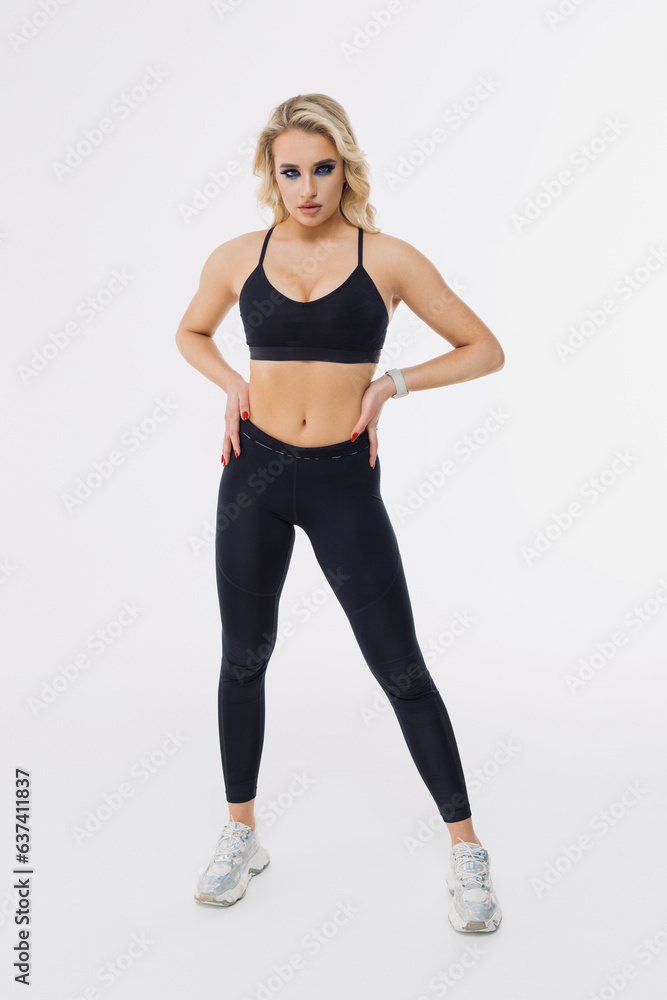 Professional sports fitness trainer in a black tracksuit on a white background. Blonde looks at the camera Professional sports fitness trainer in a black tracksuit on a white background. Blonde looks at the camera
