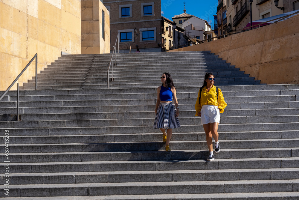 Two women friends exploring the city. Portrait of two women friends going down a staircase in Toledo, Spain.