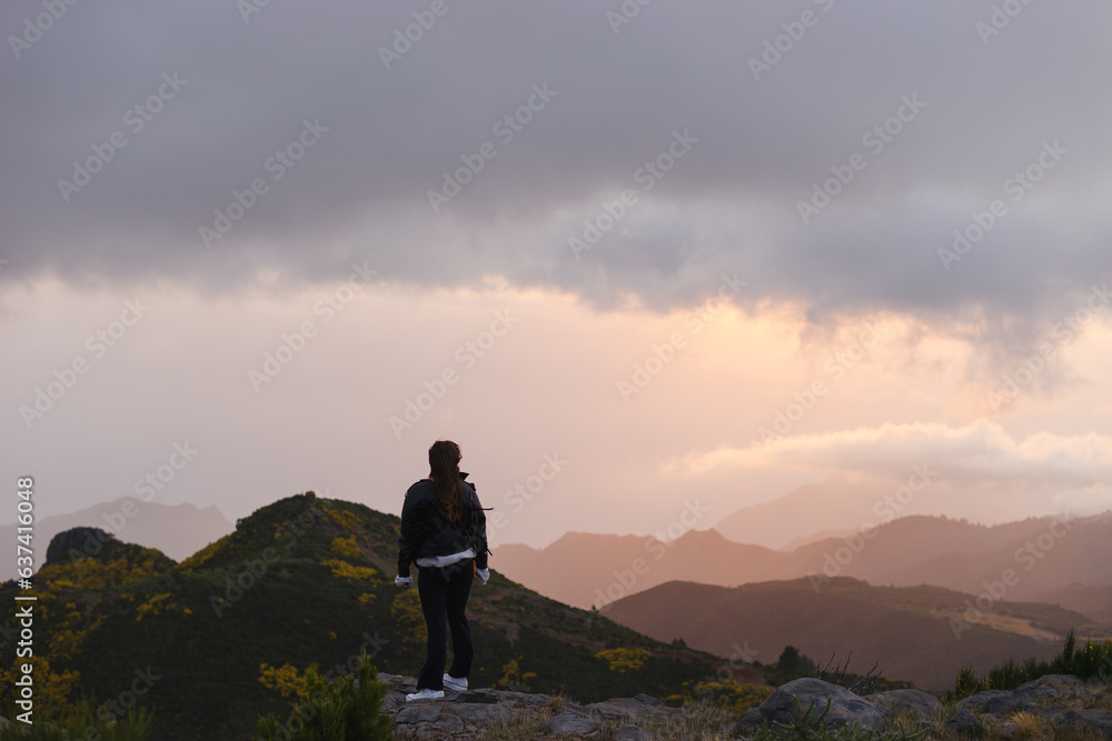 Travelling and exploring Madeira island landscapes and travel destinations. Young female tourist enjoying the sunrise and outdoor spectacular scenery. Summer tourism by Atlantic ocean and mountains. Travelling and exploring Madeira island landscapes and travel destinations. Young female tourist enjoying the sunrise and outdoor spectacular scenery. Summer tourism by Atlantic ocean and mountains.