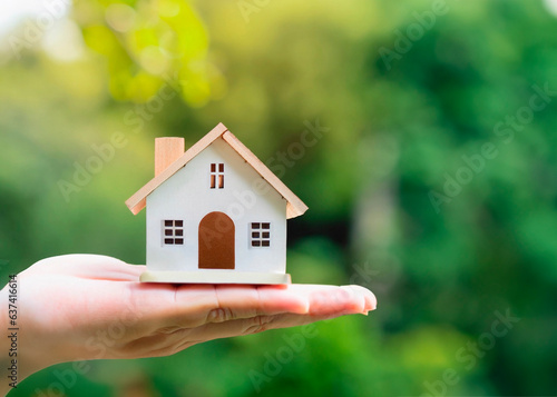 Hand holding a miniature of a beautiful house with doors and windows, civil construction, housing.