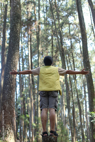 Rear view of young man feel freedom, open arms with trees on background. 
