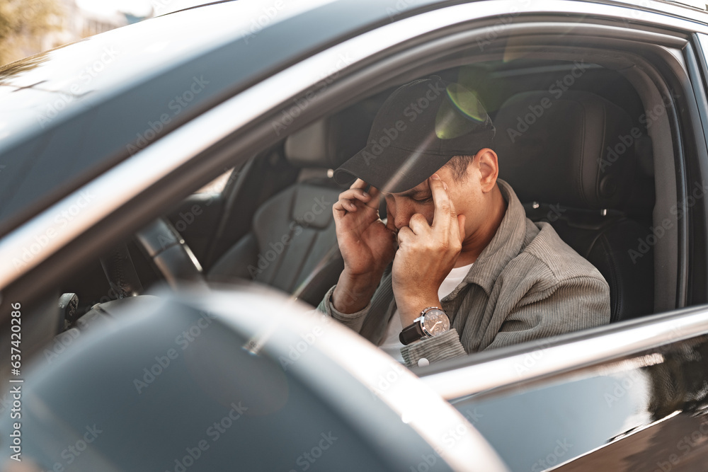 Annoyed tired young man driving his car with open window