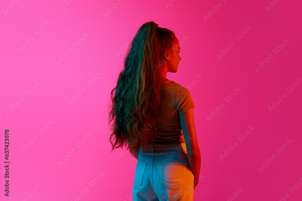 Back view of young girl with long curly hair in ponytail standing and ...