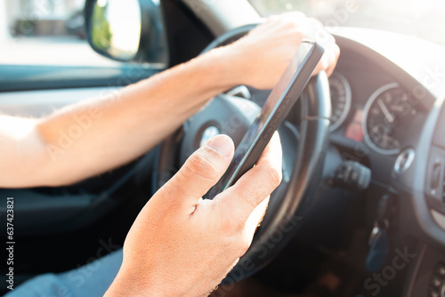 Hands of man driver using mobile phone while driving. Road danger concept