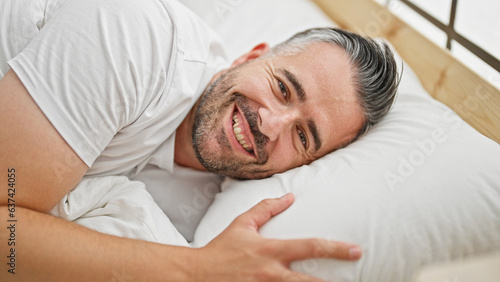 Grey-haired man smiling confident lying on bed at bedroom