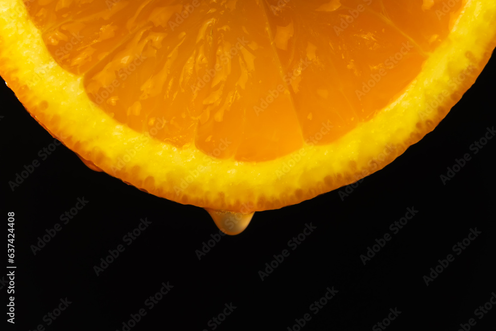 Macro photography, a drop of juice dripping from a slice of orange on a ...