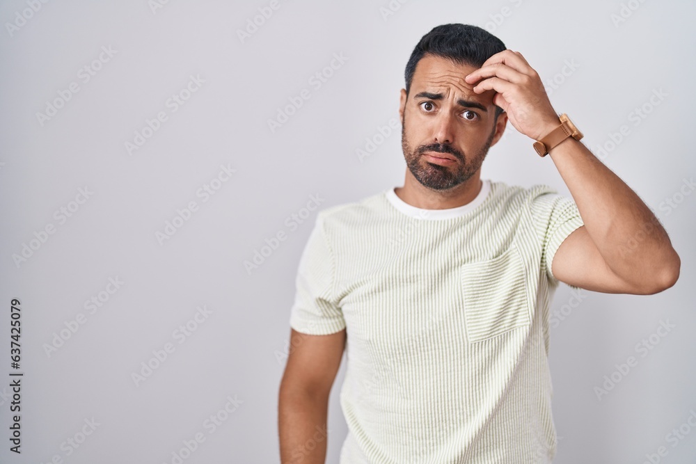 Hispanic man with beard standing over isolated background worried and stressed about a problem with hand on forehead, nervous and anxious for crisis Hispanic man with beard standing over isolated background worried and stressed about a problem with hand on forehead, nervous and anxious for crisis