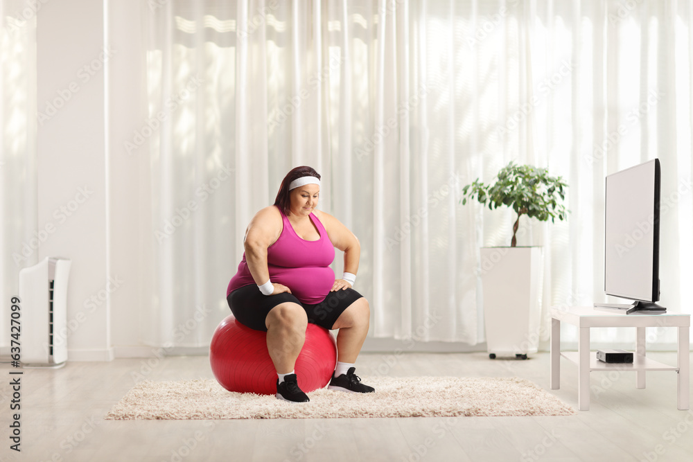 Overweight woman sitting on a fintess ball and thinking Overweight woman sitting on a fintess ball and thinking