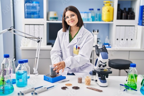 Young beautiful hispanic woman scientist smiling confident weighing sample at laboratory