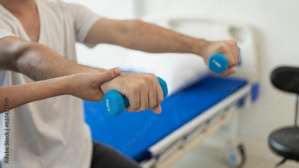 Doctors, physiotherapists treat patients with rehabilitation arm pain, do physiotherapy by treating his therapist in stretching in the clinic. Remote Picture - obrazy, fototapety, plakaty 