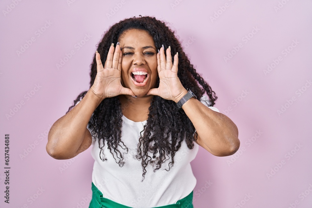 Plus size hispanic woman standing over pink background smiling cheerful playing peek a boo with hands showing face. surprised and exited Plus size hispanic woman standing over pink background smiling cheerful playing peek a boo with hands showing face. surprised and exited