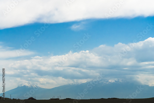 Across the field in the distance is the snow-covered Mount Ararat against a blue sky with clouds