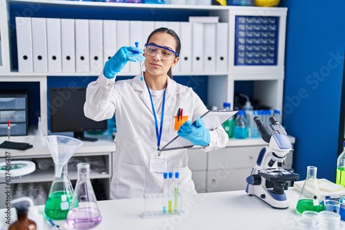 Young hispanic woman scientist holding test tube at laboratory
