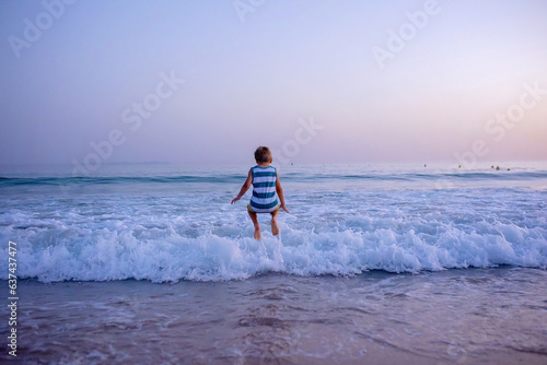 Happy children, playing on the beach on sunset, kids running in the water in the ocean