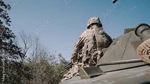 An armed American soldier rides in a combat vehicle with an M4 assault rifle