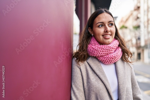 Young beautiful hispanic woman wearing scarf looking to the side at street