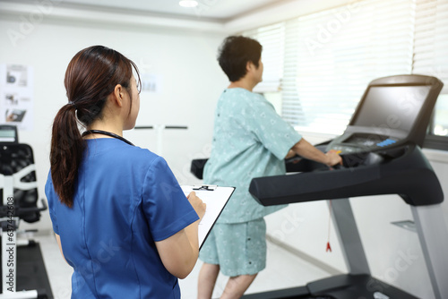 병원에서 재활치료사가 런닝머신 위 환자의 상태를 기록하며 회복을 돕는 모습