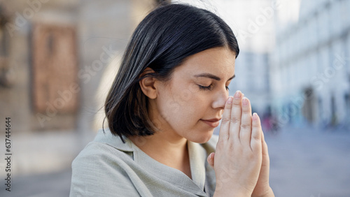 Photography Young beautiful hispanic woman praying with closed eyes in the streets of Vienna