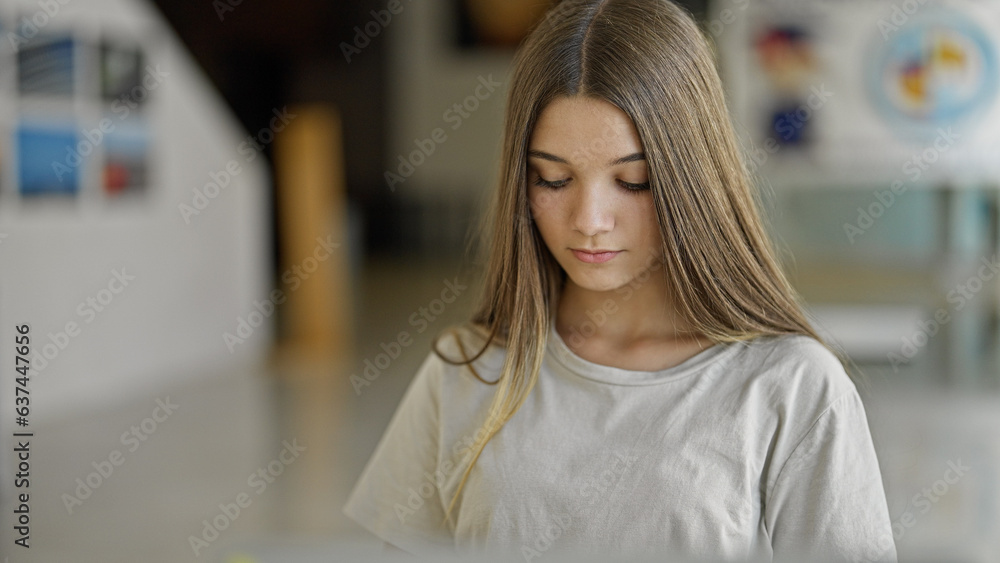 Obraz premium Young beautiful girl sitting on table with serious face at library