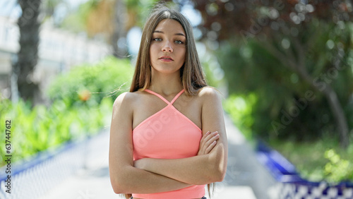 Young beautiful girl standing with serious expression and arms crossed gesture at park